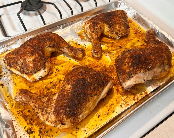 Oven baked chicken quarters coming out of the oven.