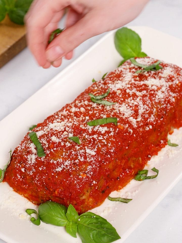 Topping our turkey meatloaf with parmesan cheese and fresh basil.