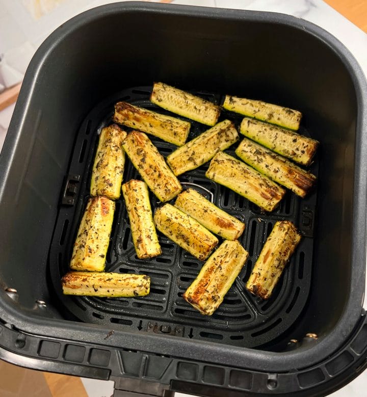 Roasted zucchini in an air fryer basket.