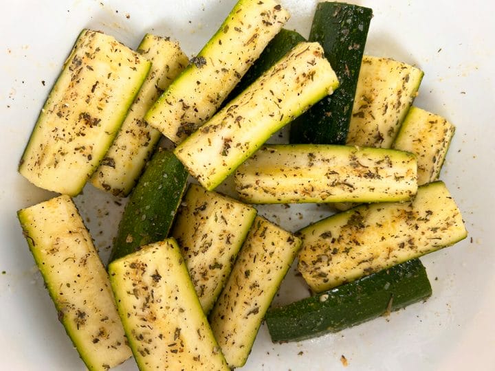 Seasoned zucchini spears to be roasted in an air fryer.