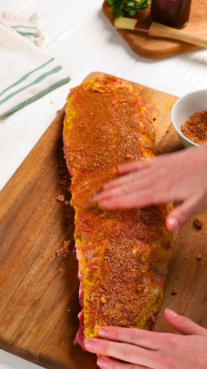 Adding seasoning rub to our best damn oven baked ribs.