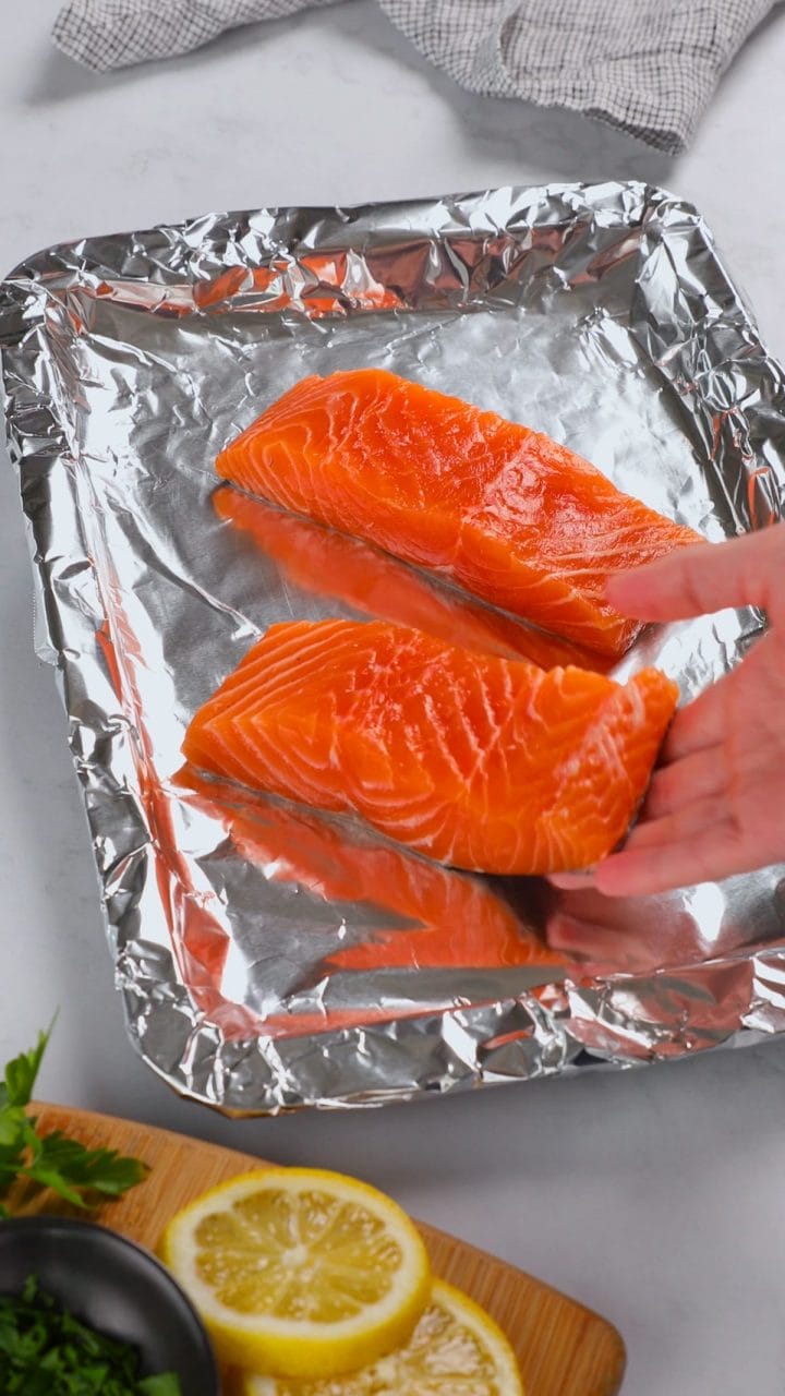 Laying salmon filets out on a foil-lined baking sheet for our honey garlic salmon recipe.