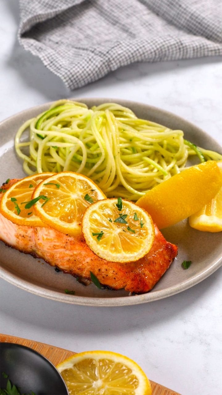 Serving honey garlic salmon filets with zoodles and lemon slices.