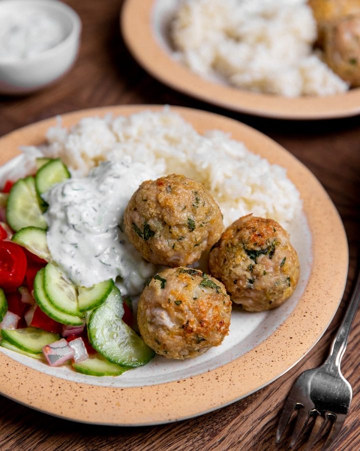 Air fryer Greek chicken meatballs served over salad and rice.