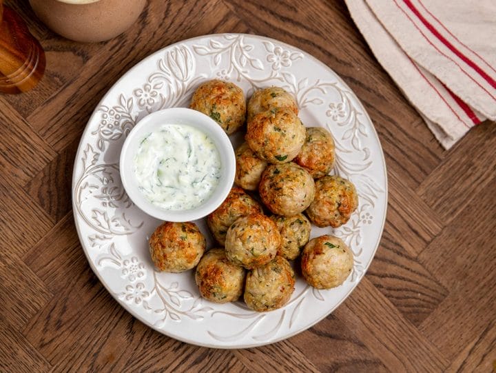 A plate of air fryer Greek style chicken meatballs served on a plate with tzatziki sauce