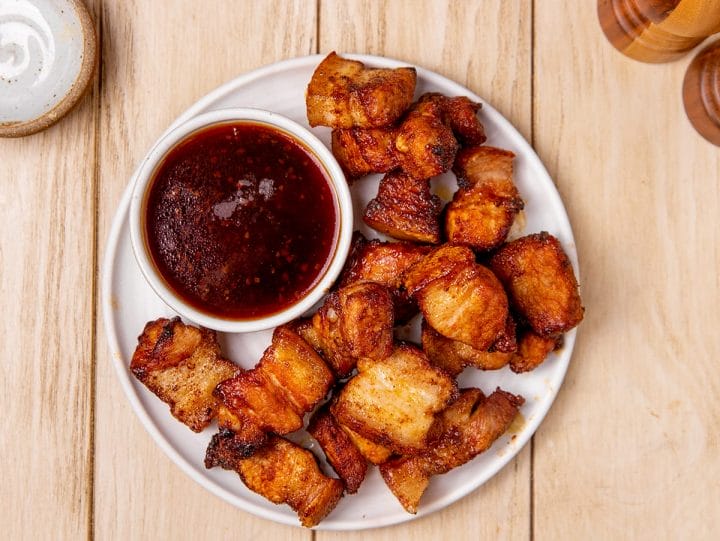 Air fryer pork belly bites served on a plate with dipping sauce.