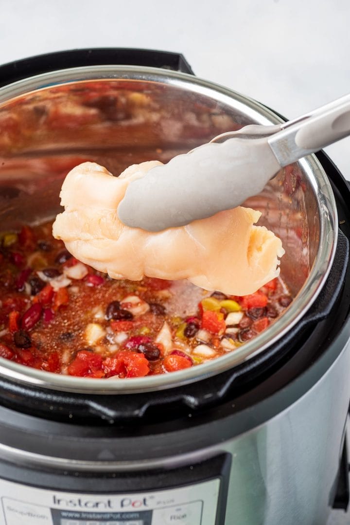Adding chicken breast to the Instant Pot to make creamy chicken chili.