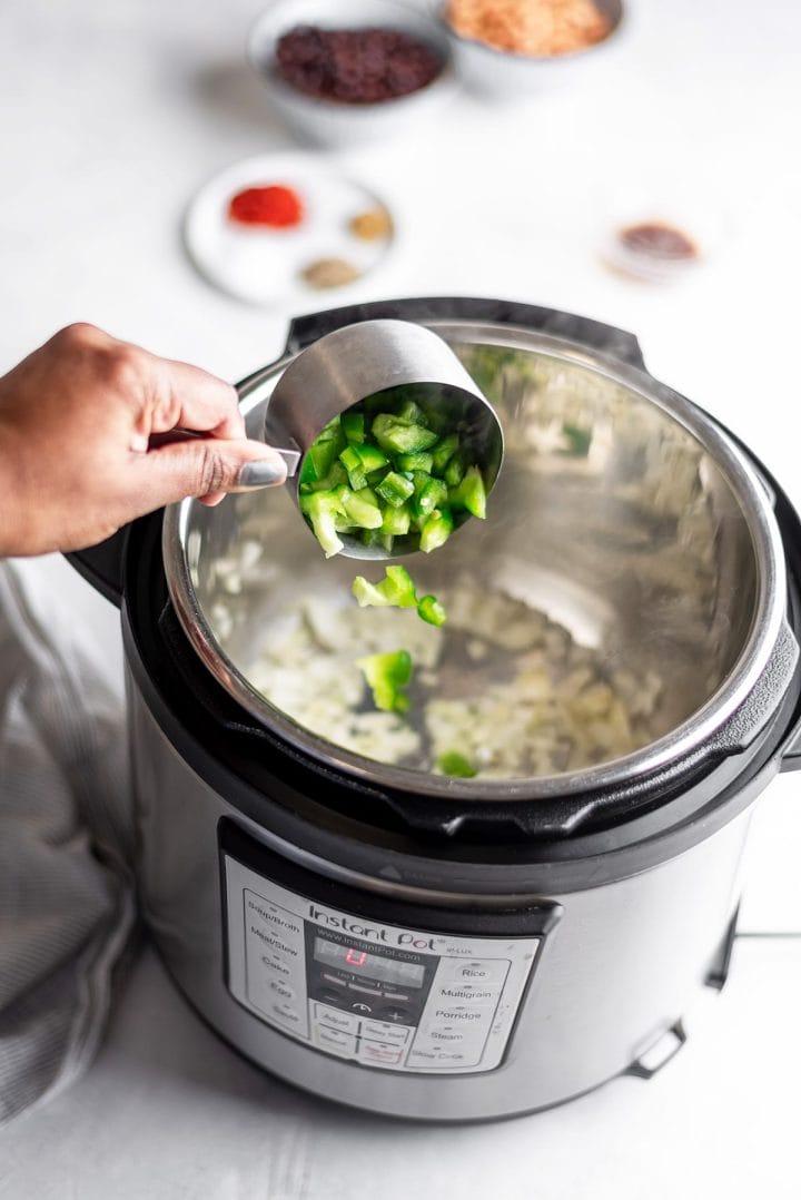 Adding green peppers to Instant Pot to saute for vegetarian chili recipe.