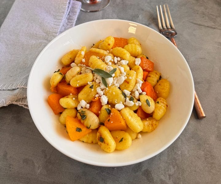A bowl of gnocchi with roasted butternut squash topped with brown butter sage sauce and goat cheese crumbles.