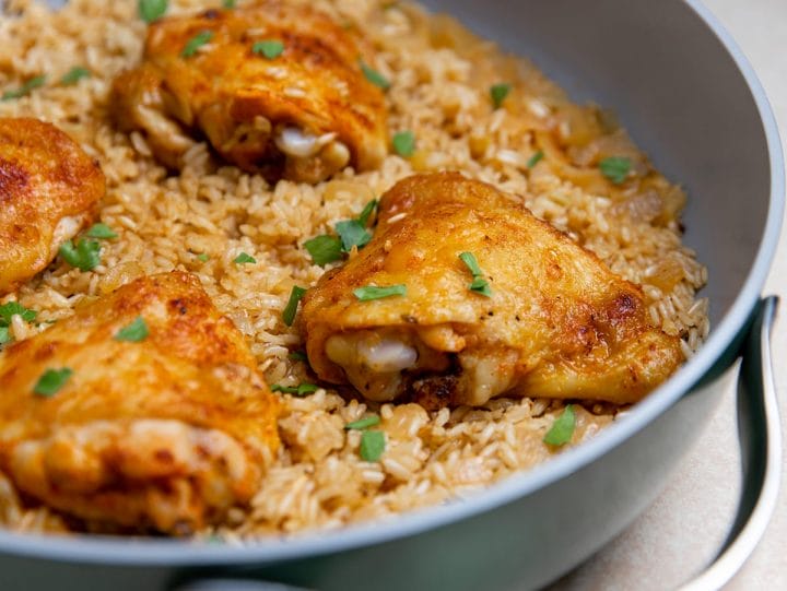 Chicken thighs cooked in a pan with brown rice ready to serve.