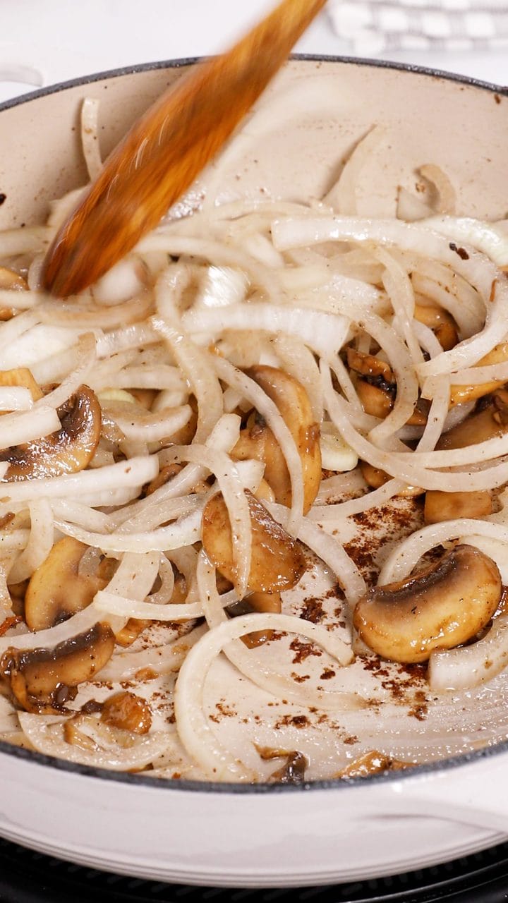 Sauteeing mushrooms and onions in a pan to make smothered pork chops.